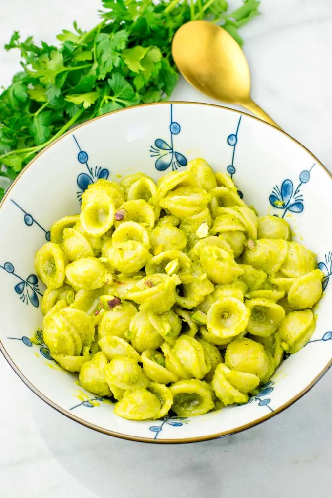 Top view of the pistachio pesto mixed with paste. Golden spoon in the background.