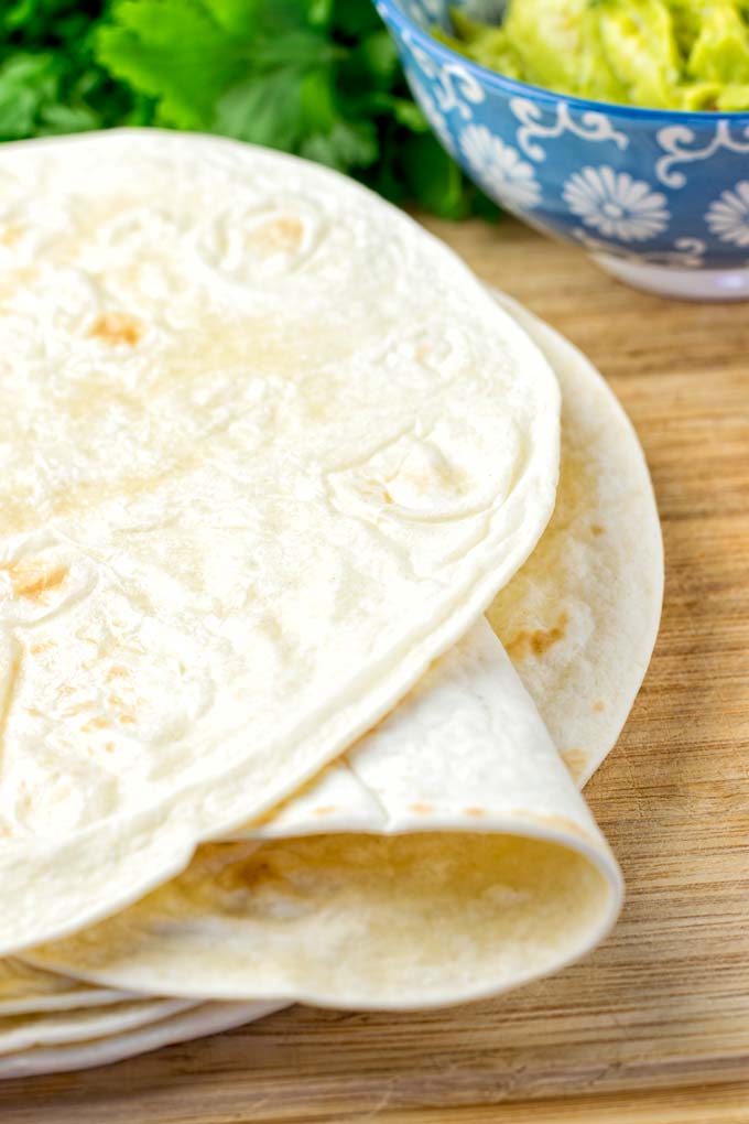 Freshly baked tortillas on a wooden board.