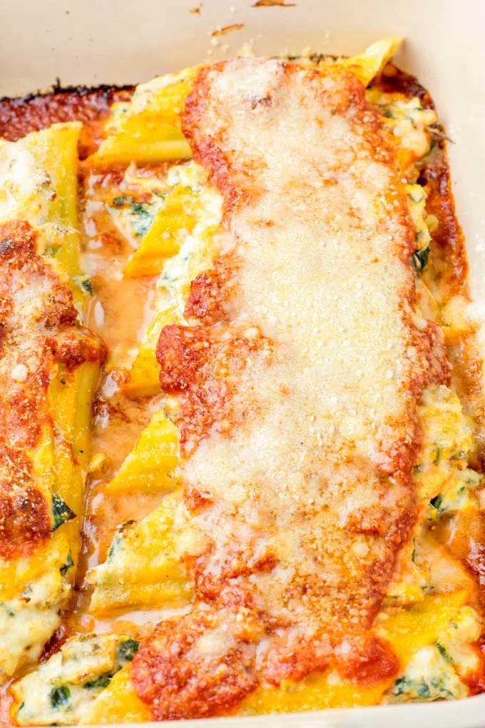 Manicotti covered with vegan cheese in a casserole.