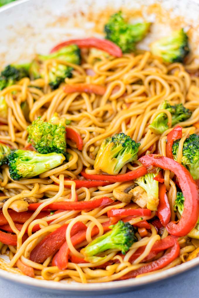 Broccoli florets and thin bell pepper slices with wok noodles.