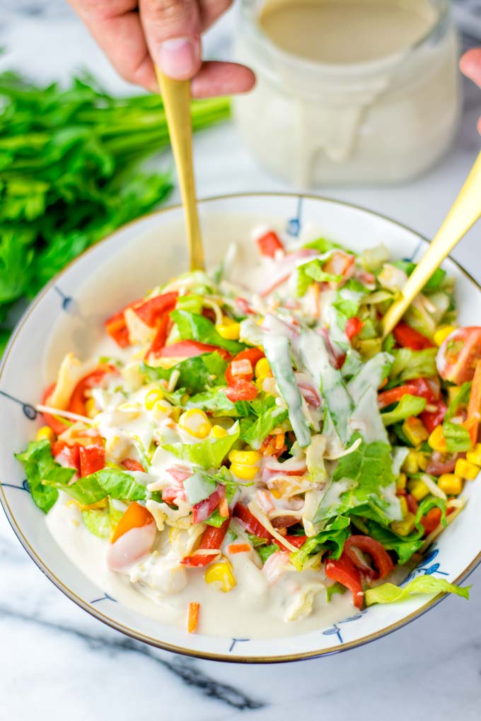 Shown mixing the Tahini Dressing and the fresh salad in a small bowl.