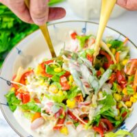 Golden spoons in the mixed fresh salad.