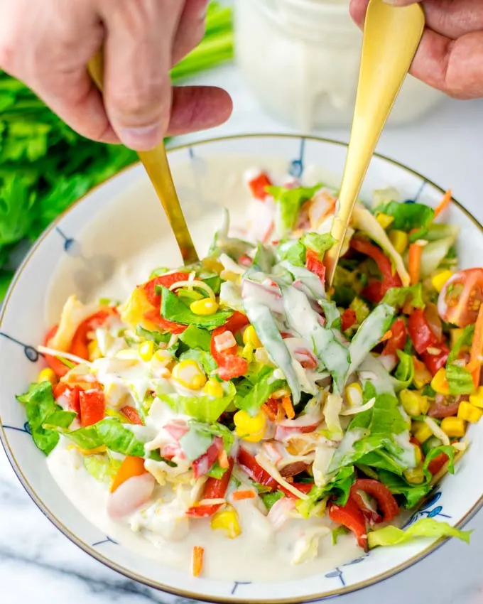 Golden spoons in the mixed fresh salad.