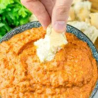 Dipping roasted bread into the Romesco Dipping Sauce