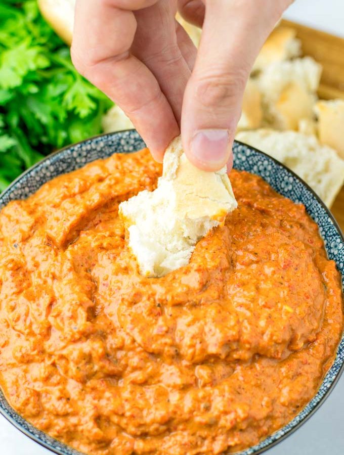 Dipping roasted bread into the Romesco Dipping Sauce