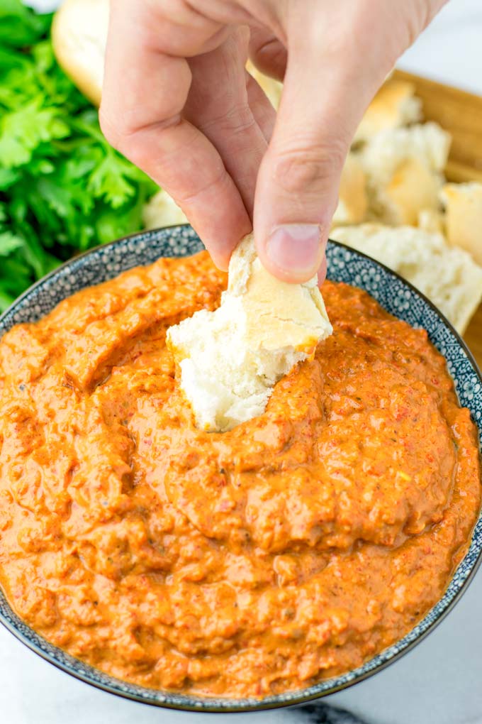 Dipping roasted bread into the Romesco Dipping Sauce