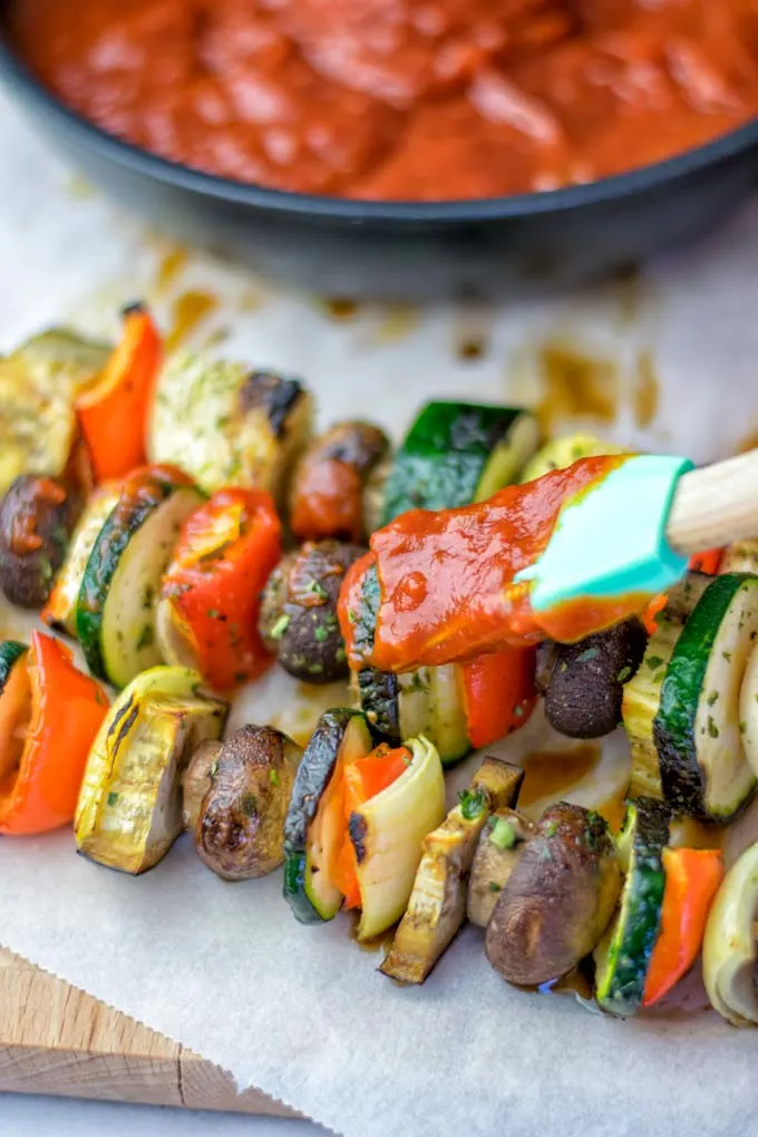 Coating veggie skewers with the Sugar Free BBQ sauce.