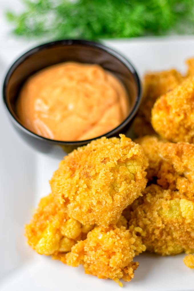 Plate full of fried Bang Bang Cauliflower with extra Bang Bang sauce for dipping.