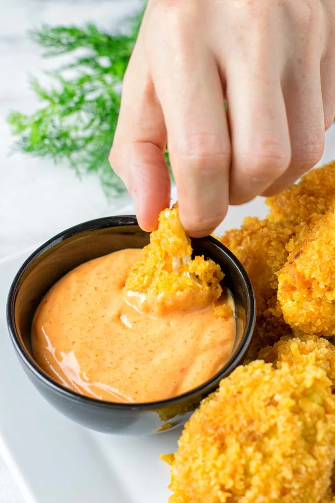 Dipping one cauliflower floret into the extra dipping sauce.