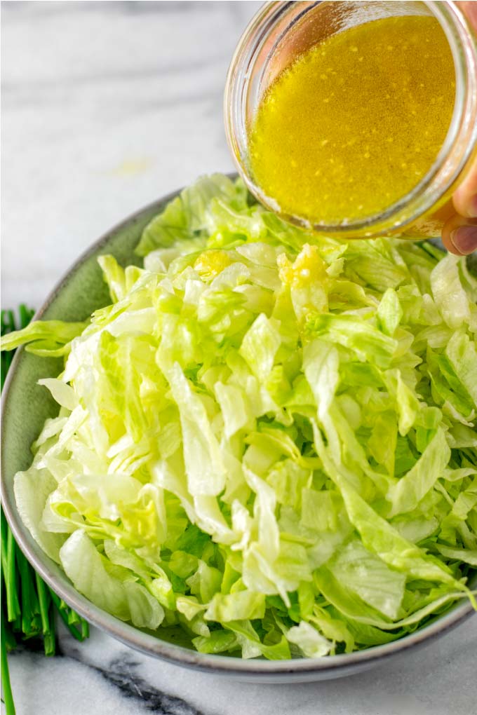 Pouring the Lemon Vinaigrette over a green salad.