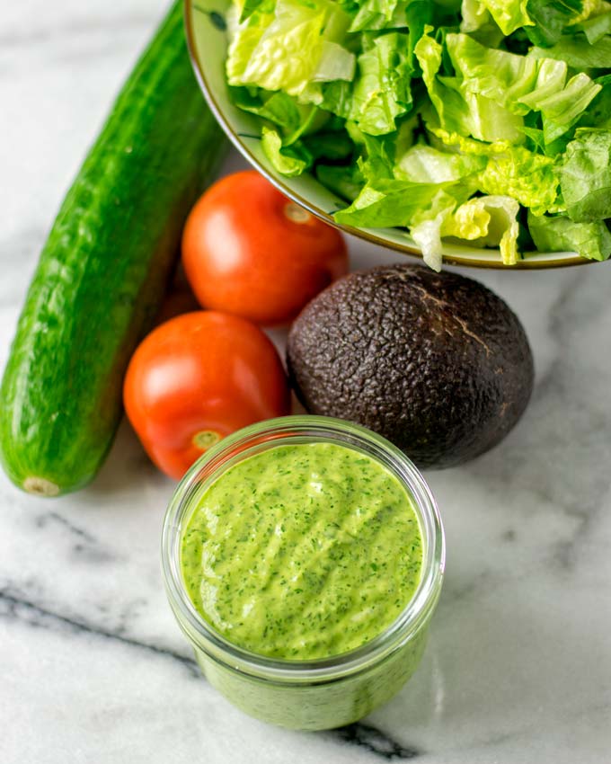 Jar of the dressing with salad ingredients in the background.