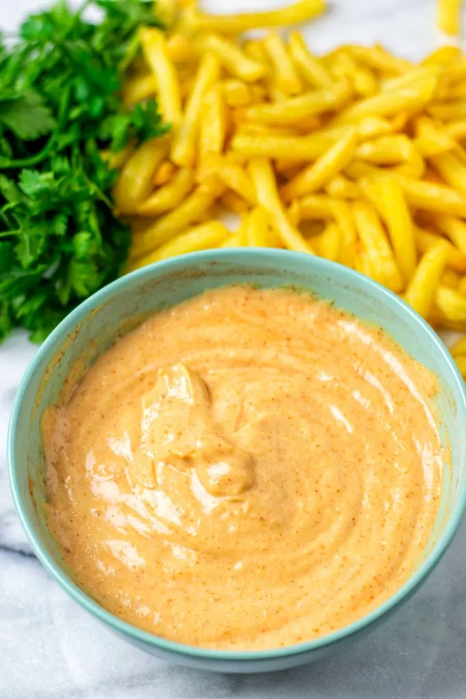 Showing the sauce in front of a bed of fries.