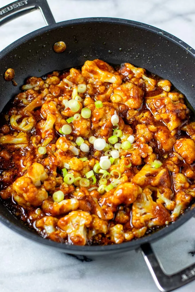 Sweet and Sour Cauliflower ready in a pan with some scallions on top.