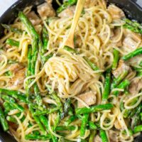 Top view on a sauce pan full of the finished Asparagus Pasta dish, with a golden fork.