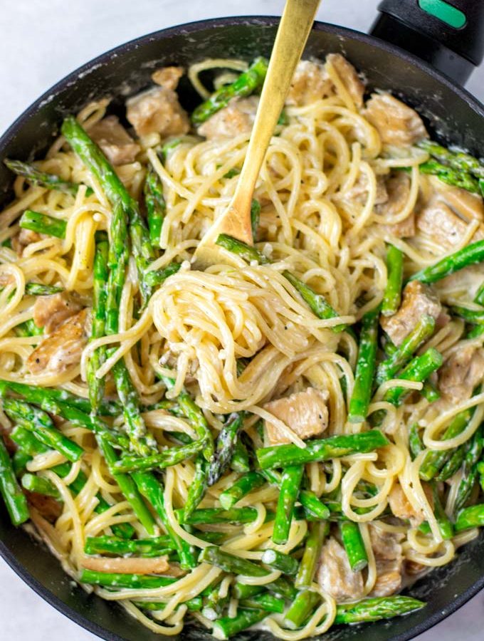 Top view on a sauce pan full of the finished Asparagus Pasta dish, with a golden fork.