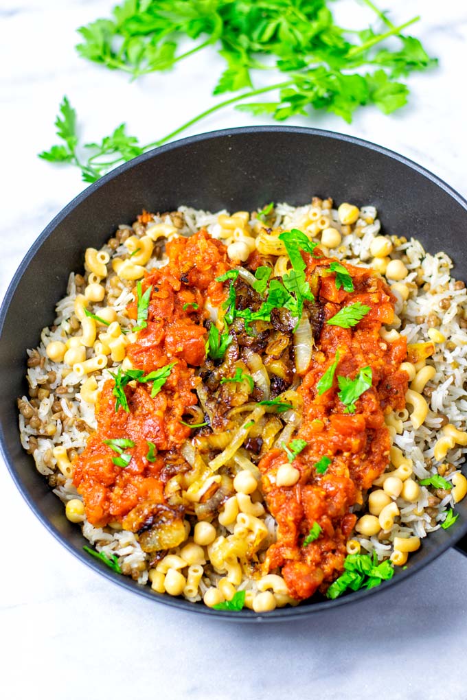 The Koshari dish in the saucepan in garnished with fresh parsely.