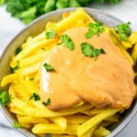 A bowl of French Fries covered in Cajun Sauce.