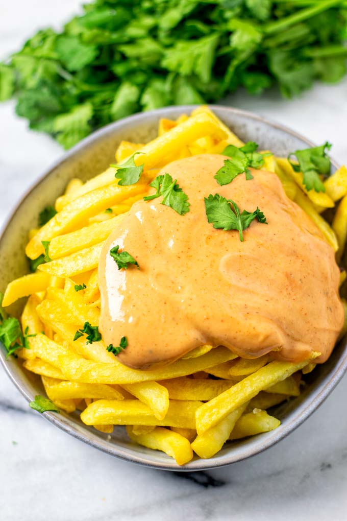 A bowl of French Fries covered in Cajun Sauce.