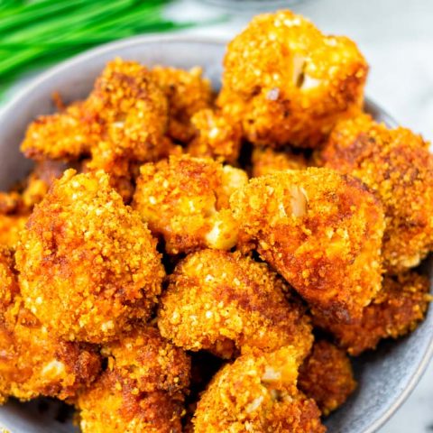 Serving bowl with ready baked Cauliflower Wings with extra dipping sauce in background.