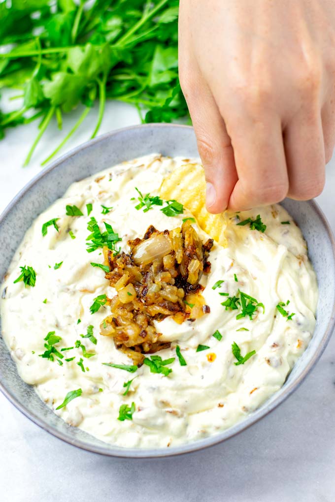 Hand dipping a potato ship into the French Onion Dip.