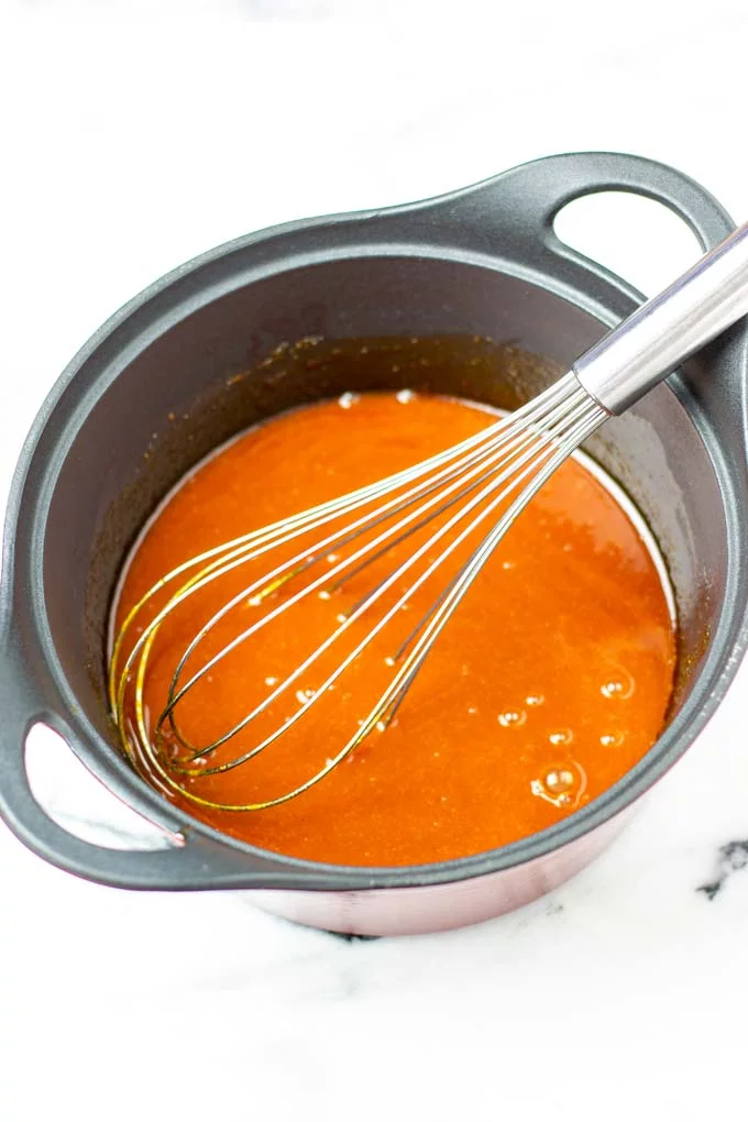 Closeup on Wing Sauce in a saucepan with wire whisk.