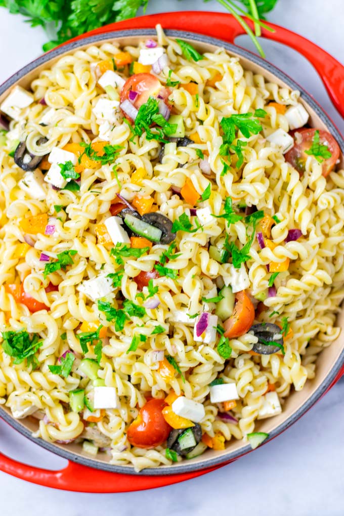 Top view on the Greek Pasta Salad with herb garnish.