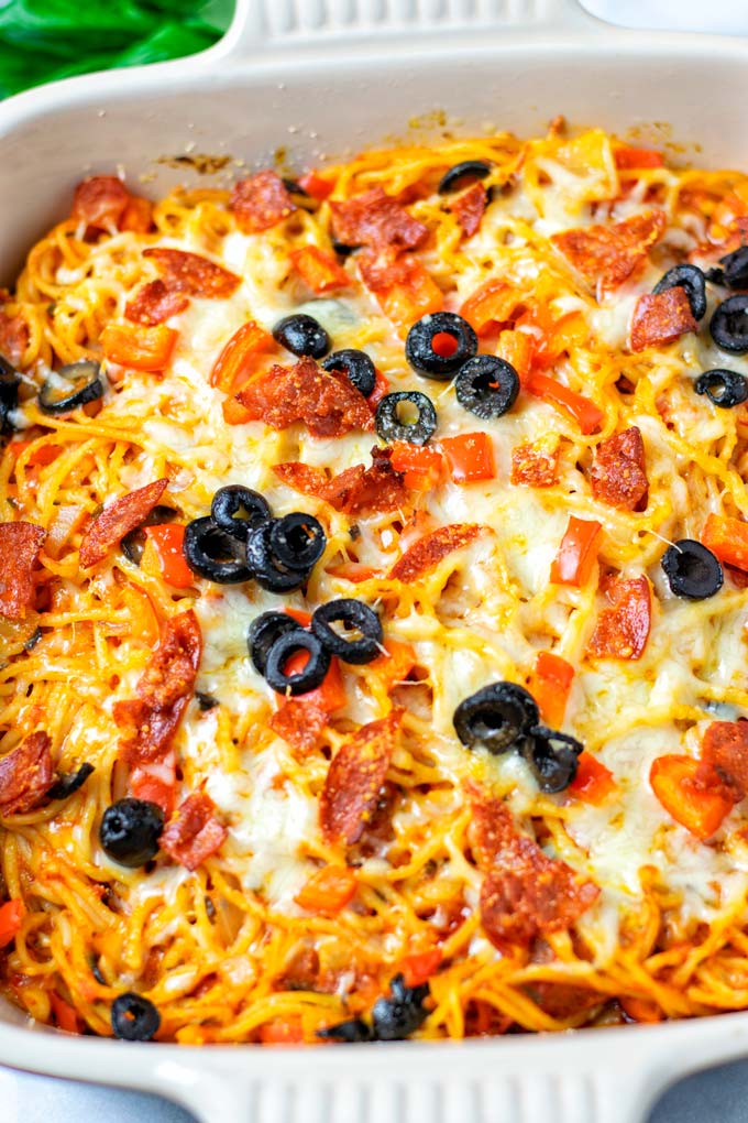 Closeup on the Pizza Spaghetti, showing Pepperoni slices, olives, and melted vegan cheese.