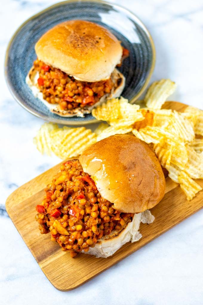 Sloppy Joes with buns on a serving board and plate, served with potato chips.