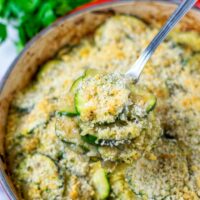 A portion of the Zucchini Casserole is lifted out of the pan with a spoon.