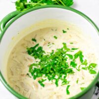 View on the finished Avgolemono Soup in a large pot with extra parsley in the background.