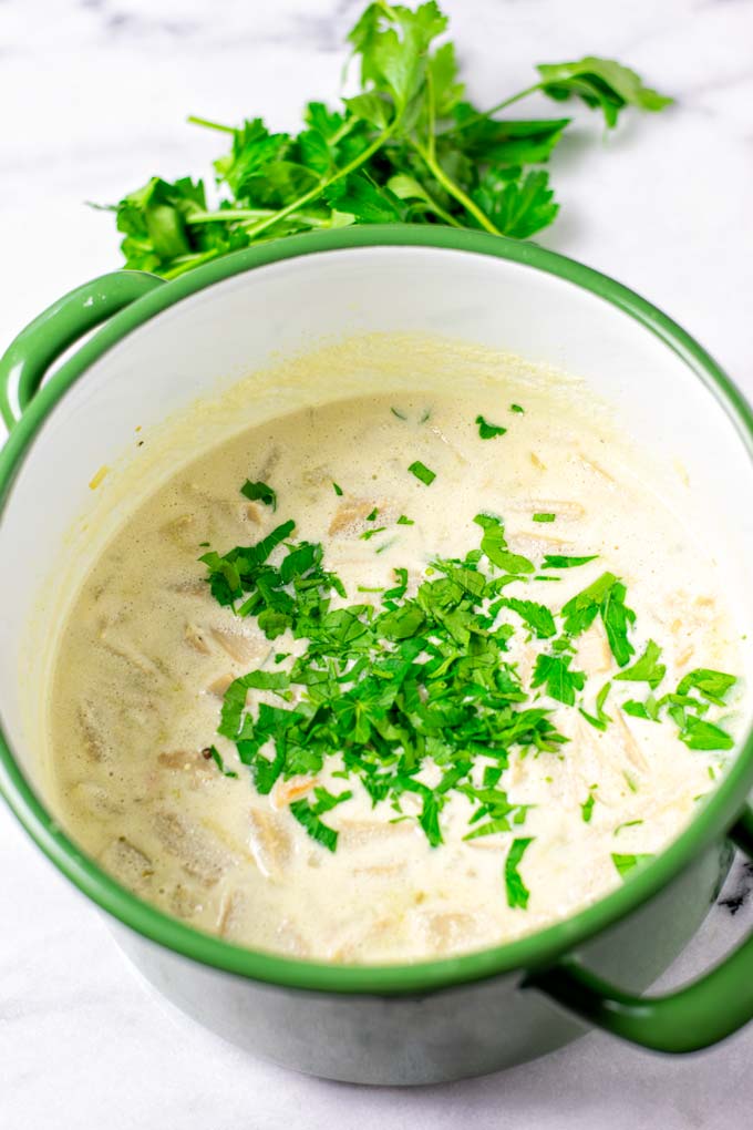 View on the finished Avgolemono Soup in a large pot with extra parsley in the background.