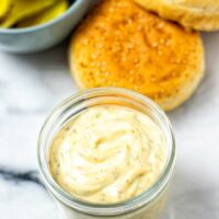 Ready Burger Sauce in the a small glass jar, with burger ingredients in the background.