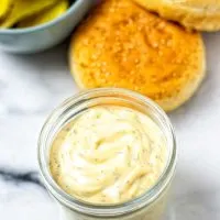 Ready Burger Sauce in the a small glass jar, with burger ingredients in the background.