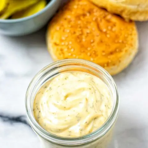 Ready Burger Sauce in the a small glass jar, with burger ingredients in the background.