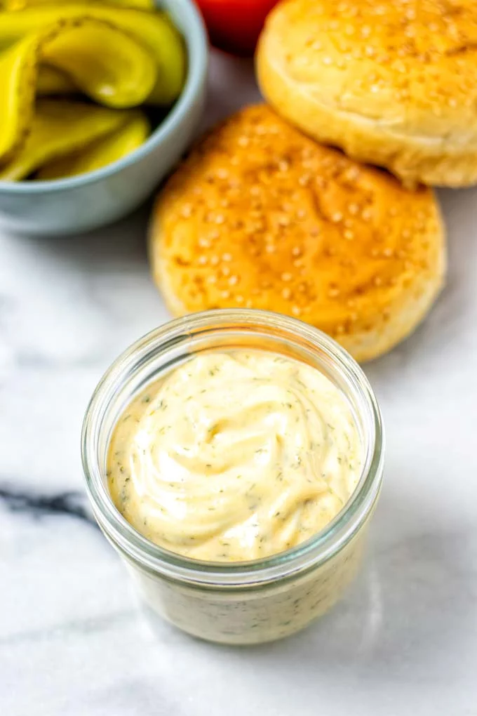 Ready Burger Sauce in the a small glass jar, with burger ingredients in the background.