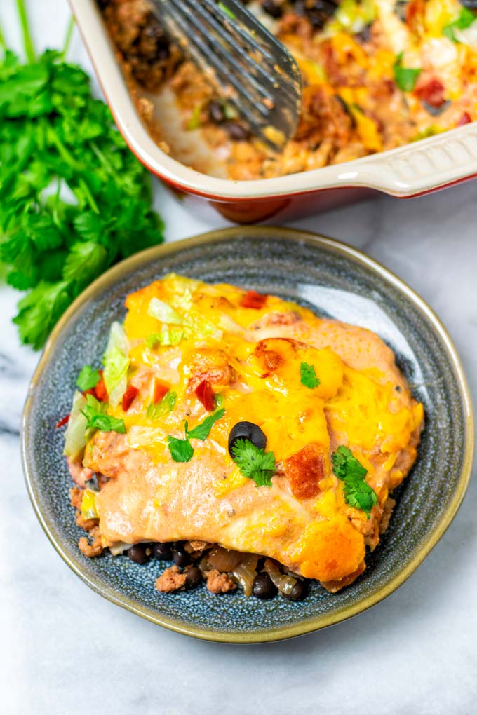 A portion of the Taco Casserole on a small dark plate with the casserole dish in the background. 