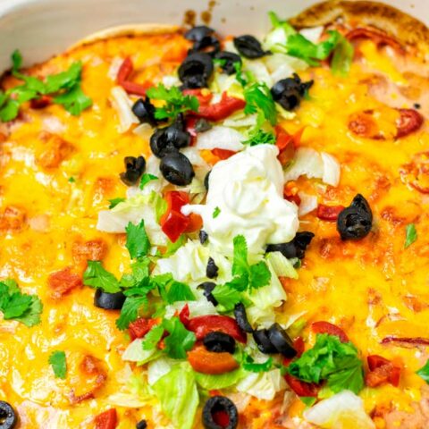 Closeup on the Taco Casserole in the casserole dish, garnished with additional vegan sour cream.