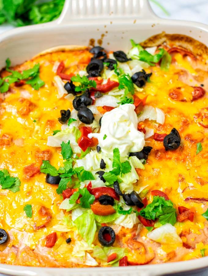 Closeup on the Taco Casserole in the casserole dish, garnished with additional vegan sour cream.