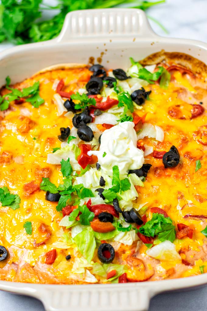 Closeup on the Taco Casserole in the casserole dish, garnished with additional vegan sour cream.