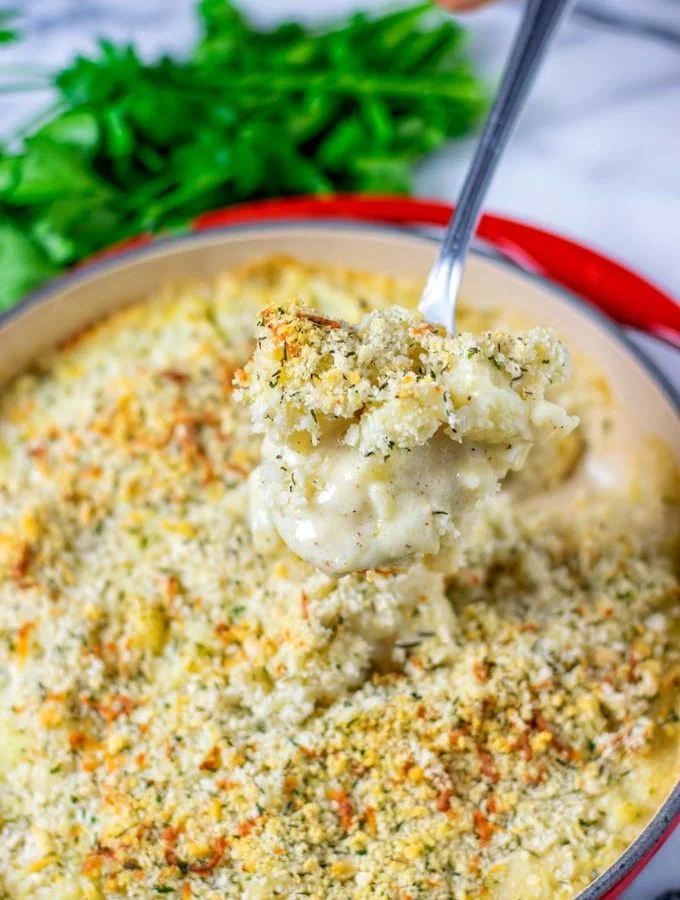 Lifting a big spoon of the Cauliflower Gratin out of the dish.