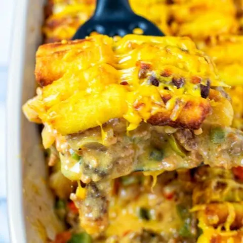 Lifting a portion of the Tater Tot Casserole out of the baking dish.