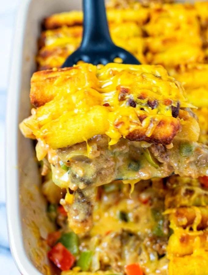 Lifting a portion of the Tater Tot Casserole out of the baking dish.