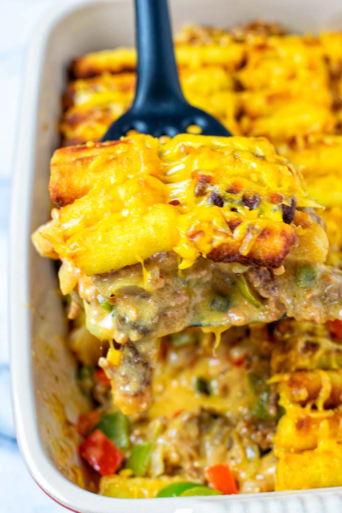 Lifting a portion of the Tater Tot Casserole out of the baking dish.