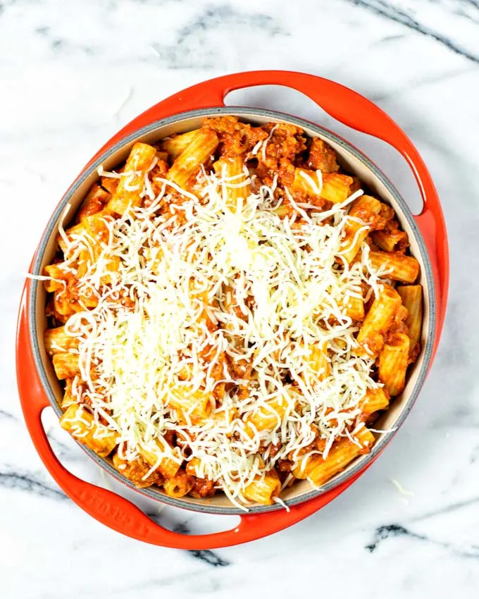 Vegan mozzarella shreds are given over the pasta in the casserole dish.