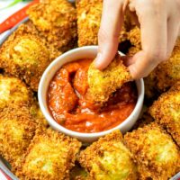 Dipping a Toasted Ravioli into the marinara sauce.