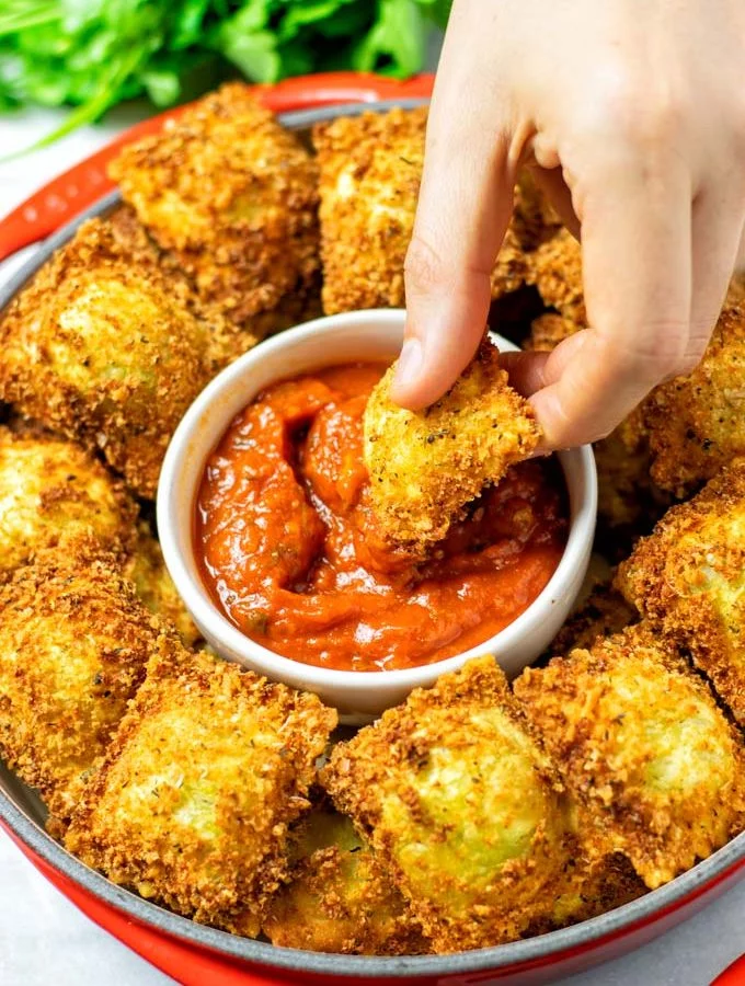 Dipping a Toasted Ravioli into the marinara sauce.