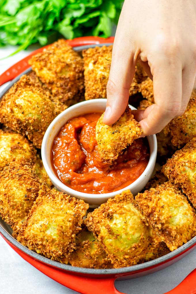 Dipping a Toasted Ravioli into the marinara sauce.