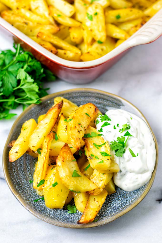 A portion of the Greek Lemon Potatoes on a small plate served with dipping sauce.