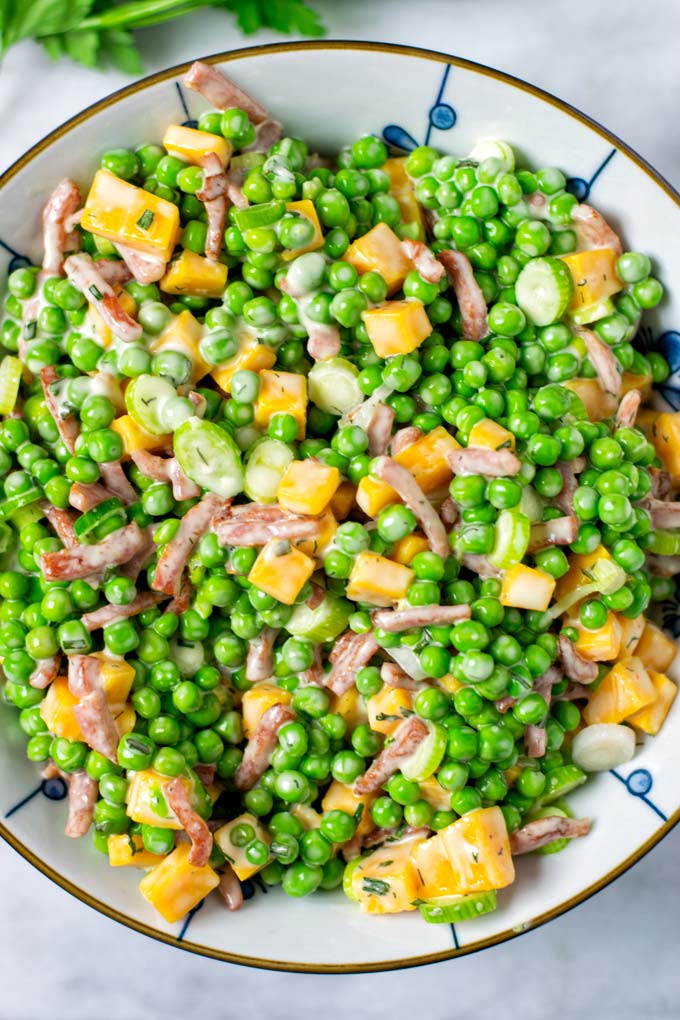 Top view on the ready Pea Salad in a white bowl.