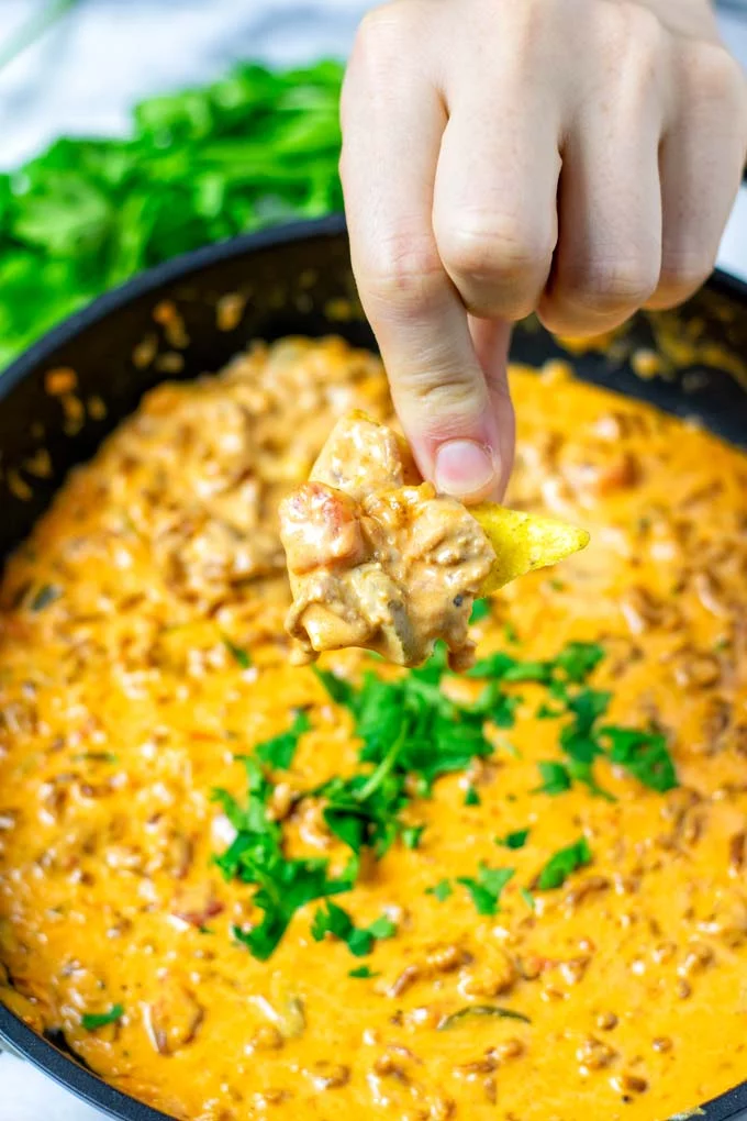 Dipping a nacho chip into the pan with the Rotel Dip.